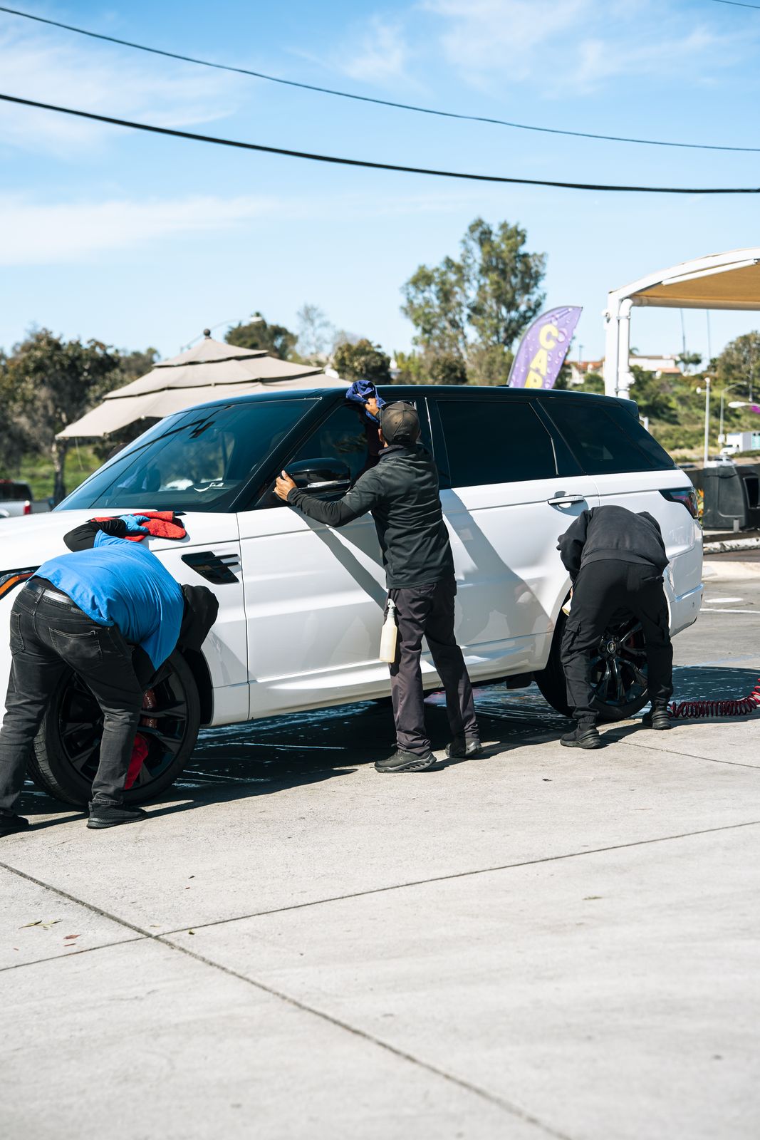 Attendants hand-cleaning the wheels of a white Range Rover