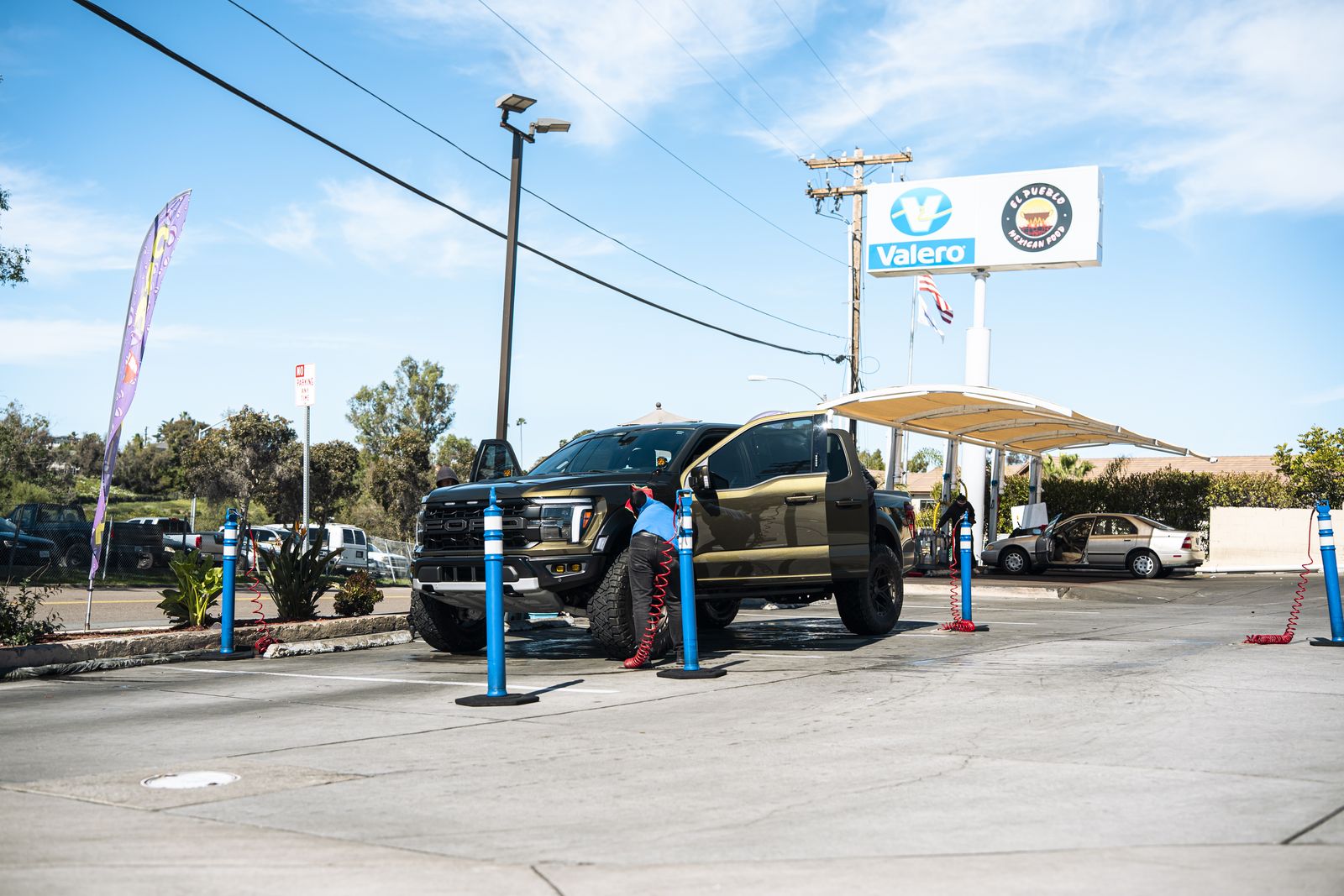 An attendant hand-washing a black GMC truck