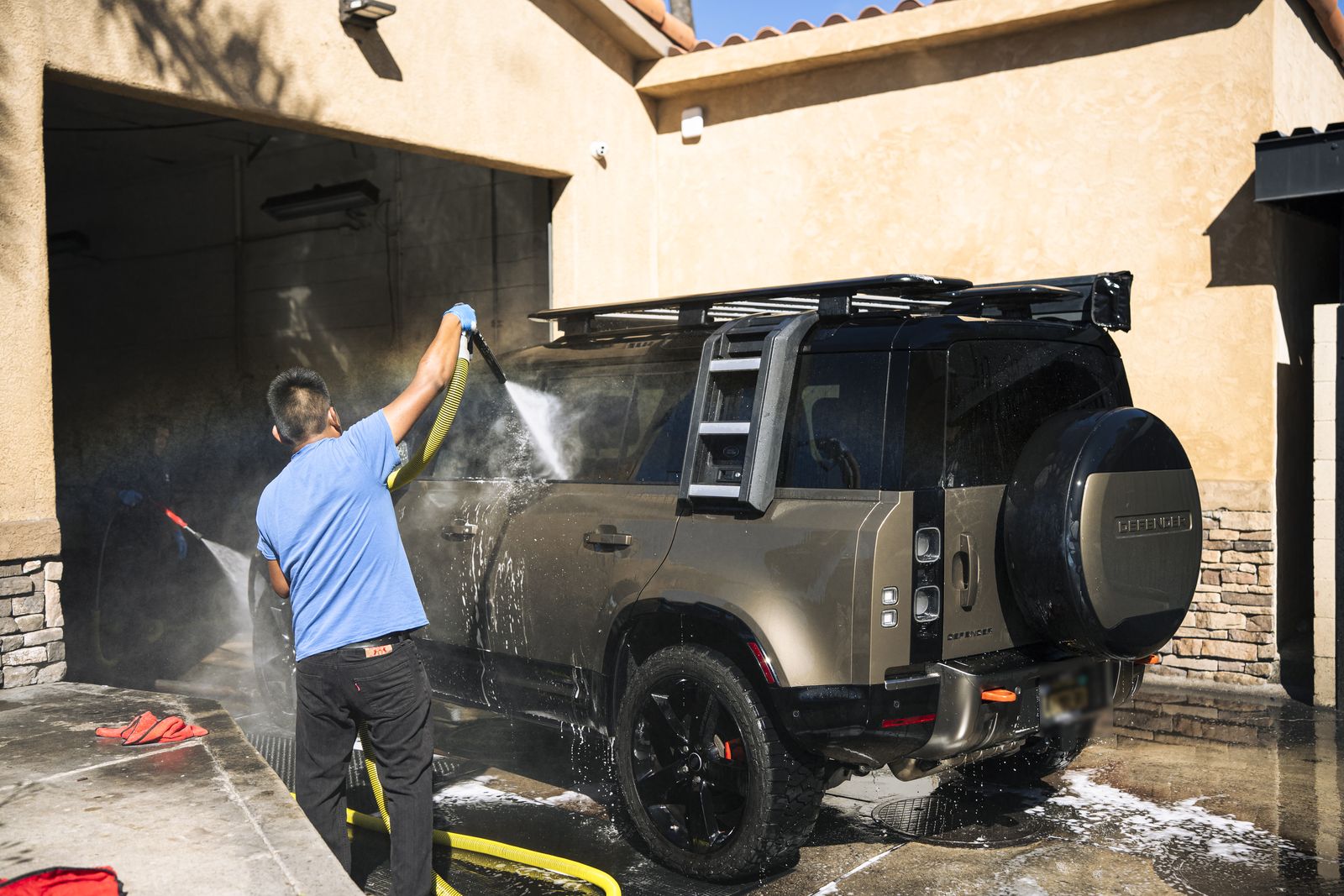 A Land Rover Defender being pressure-rinsed by hand